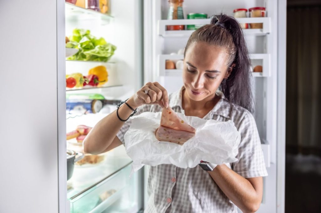 Personne vérifiant les aliments décongelés dans un congélateur après une coupure de courant.