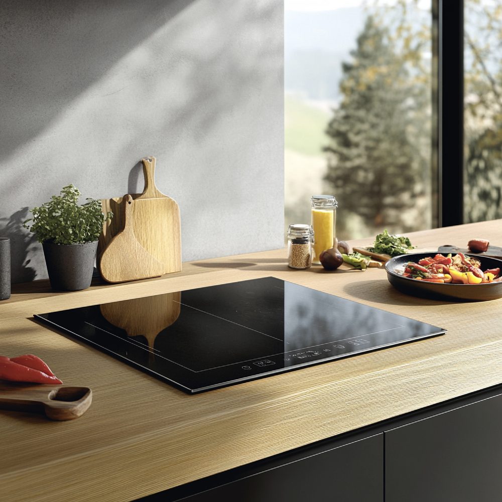 Cuisine étroite avec une plaque à induction trois feux, des casseroles et des ustensiles disposés sur le plan de travail.