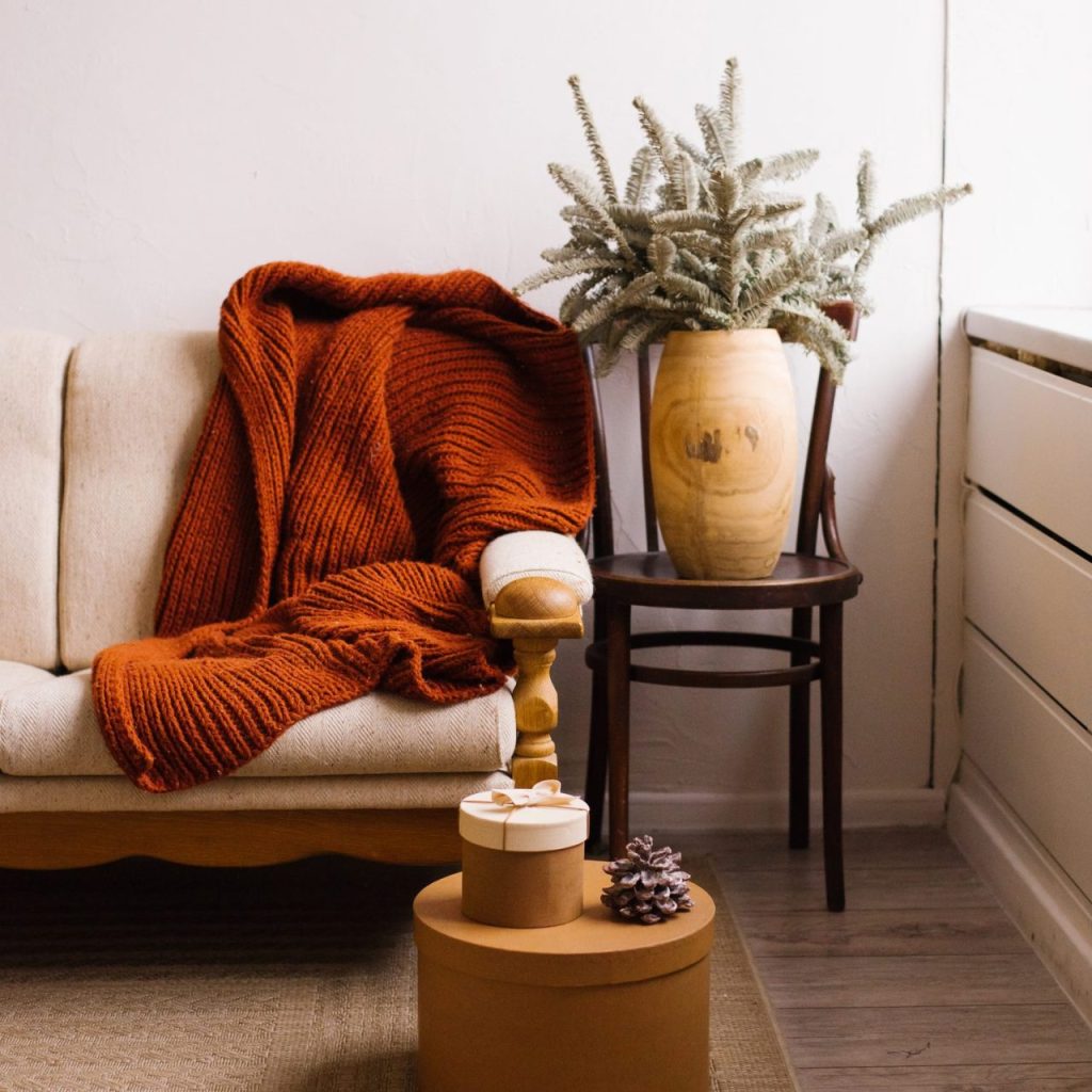 Salon existant rendu chaleureux avec des coussins, un plaid et une lumière tamisée.